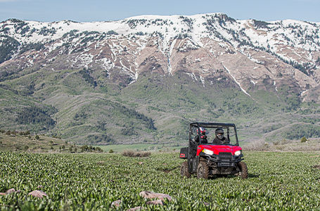 2 riders in a ranger 500 driving through a field
