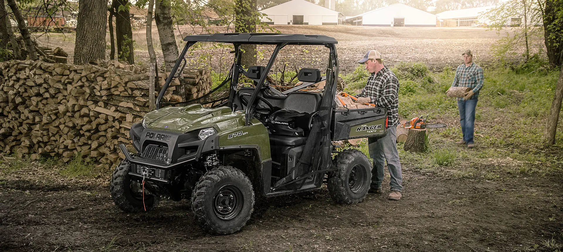 man loading wood into the cargo box on his ranger 570 full-size utv