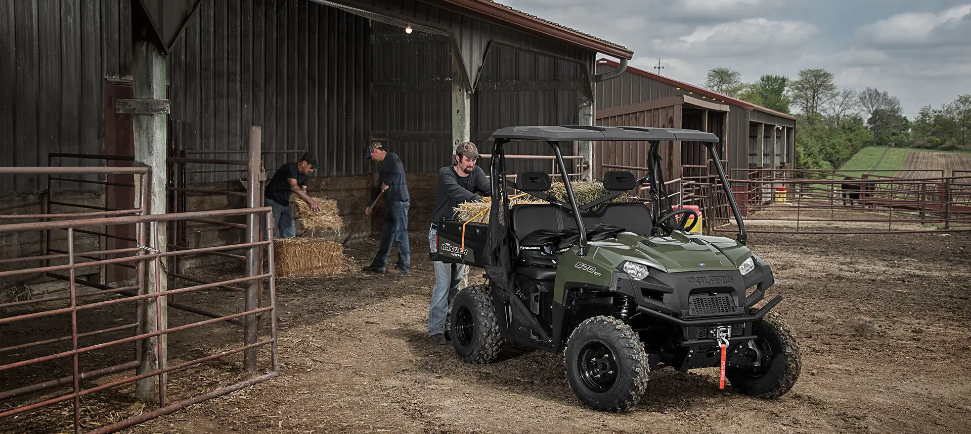 farmers loading square bales into the cargo box on their ranger 570 full-size utv