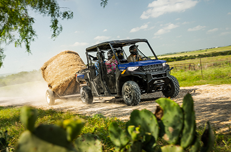 4 riders in a ranger crew 1000 pulling a trailer with a haybale