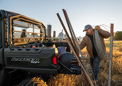 man unloading barbed-wire fence from the cargo box of his ranger sp 570