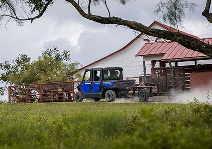 Ranger Crew SP 570 tirando de un remolque cerca de una granja