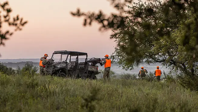 hunters unloading gear from the cargo box of their polaris ranger crew sp 570