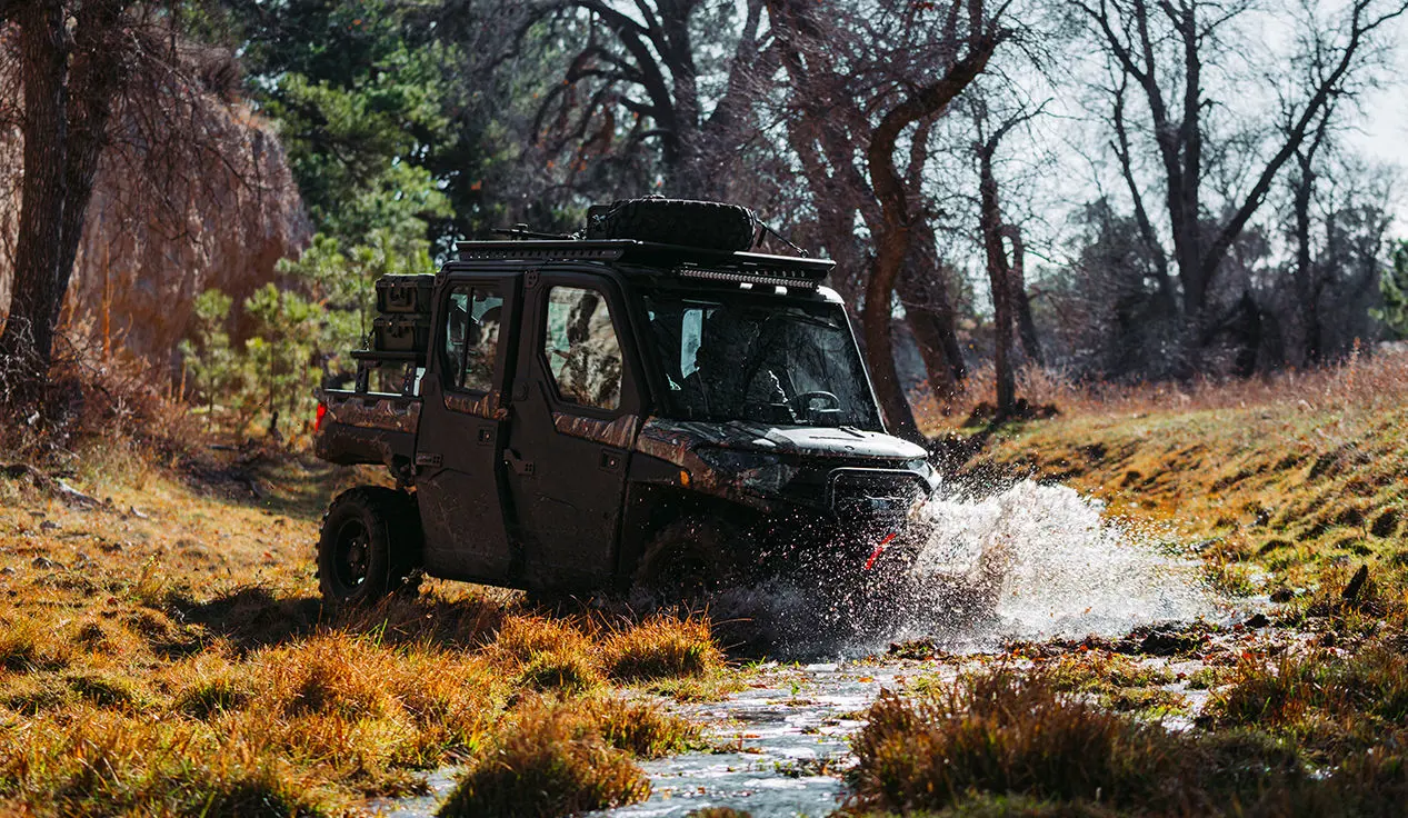 a polaris ranger crew xp 1000 northstar big game edition utv driving through a stream