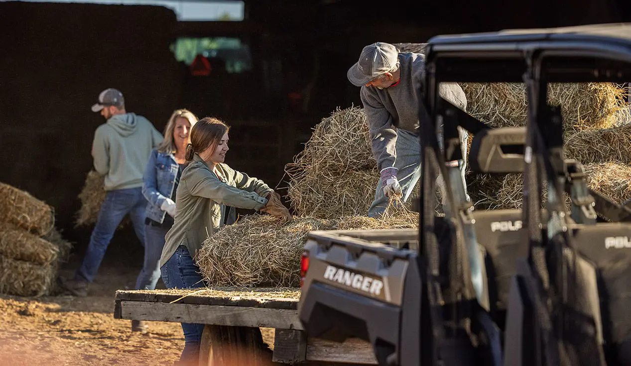familia descargando pacas cuadradas de un remolque enganchado a su ranger crew xp 1000