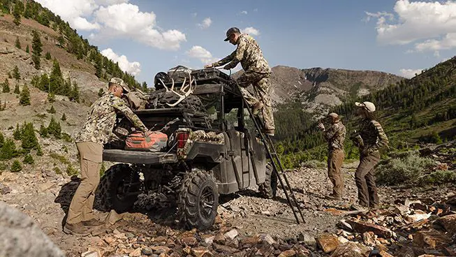 cazadores descargando equipo de la caja de carga y portaequipajes de techo rhino rack en su ranger crew xp 1000