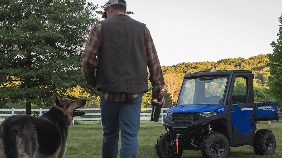 Man and dog walking to Ranger SP 570 on a farm