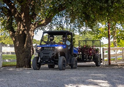 2 riders in a Ranger SP 570 pulling a trailer with flowers