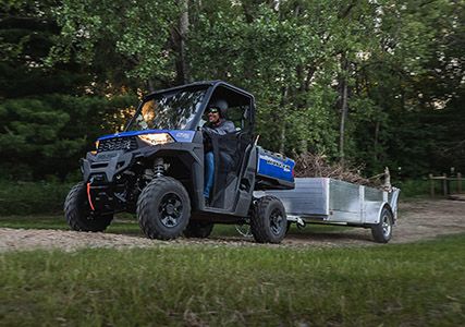 Rider in a Ranger SP 570 pulling a trailer with firewood