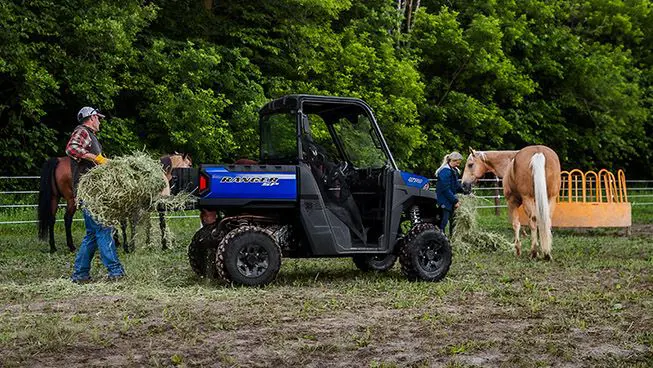 Man unloading a square bale from the cargo box of his RANGER SP 570