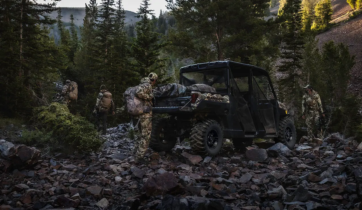 hunter unloading gear from the cargo box of a polaris ranger xp 1000 big game edition utv