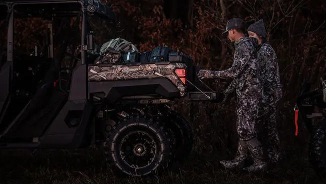 2 hunters loading gear into the cargo box of a polaris ranger xp 1000 big game edition utv