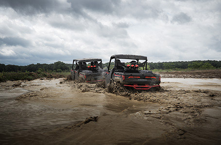 2 polaris ranger xp 1000 high lifters driving through deep mud