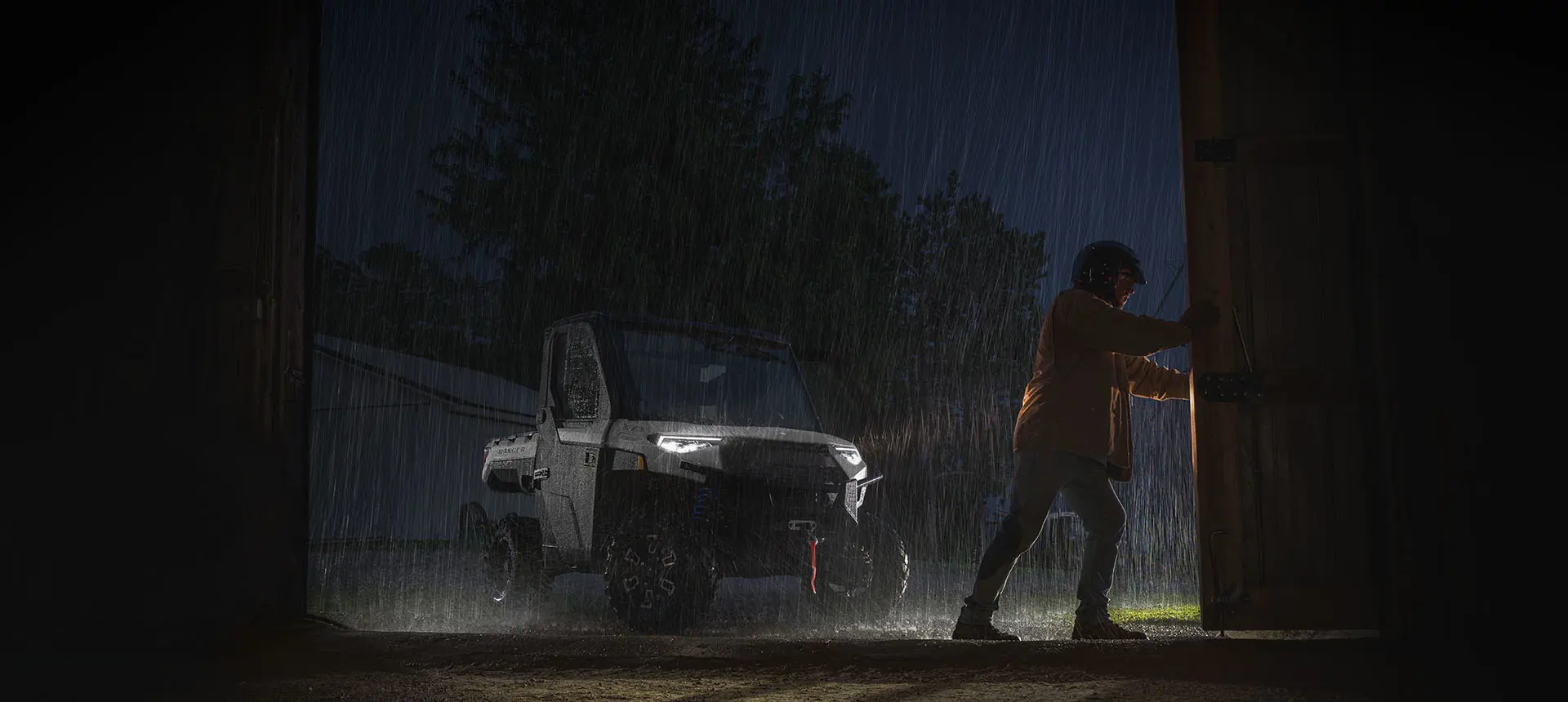 Ranger XP 1000 NorthStar Edition bajo la lluvia mientras un hombre abre la puerta del cobertizo