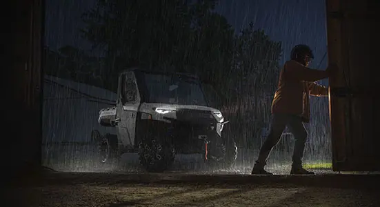 Ranger XP 1000 NorthStar Edition bajo la lluvia mientras un hombre abre la puerta del cobertizo