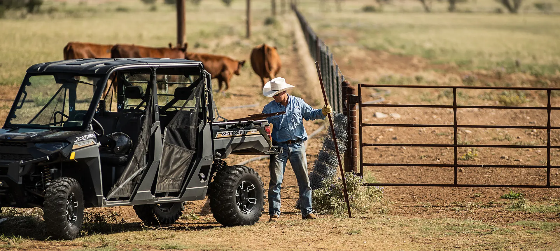 man unloading fence posts from the cargo box of his ranger crew xp 1000 texas edition