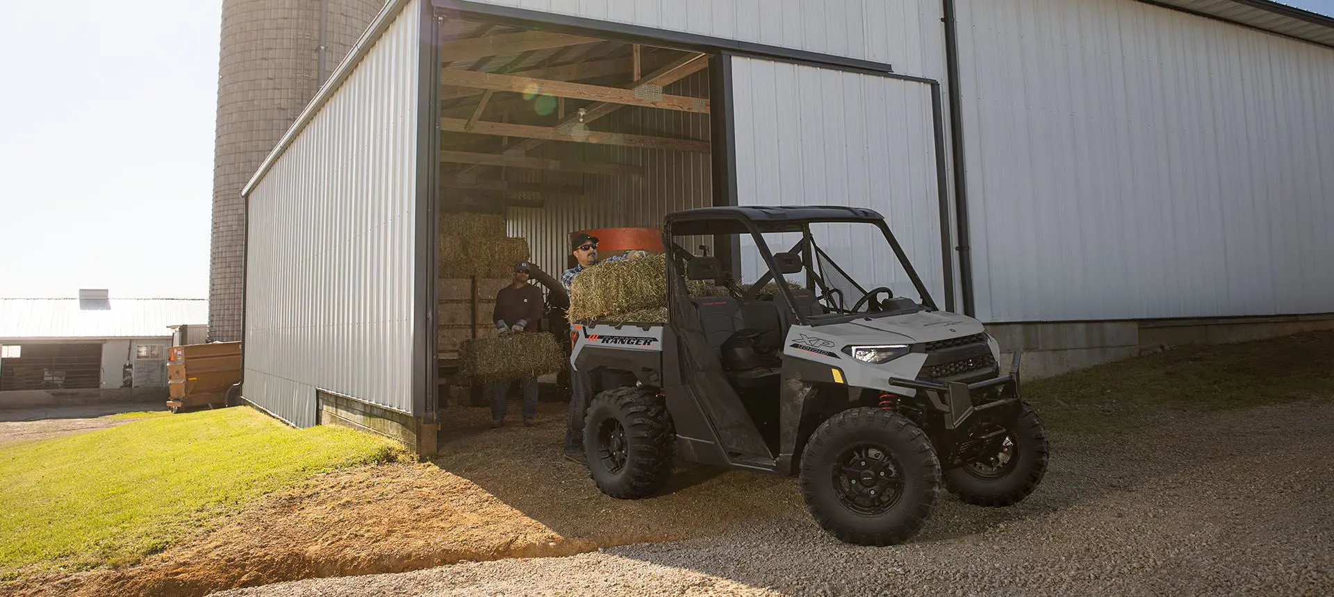 2 men loading square bales into cargo box on their Ranger XP 1000 Trail Boss