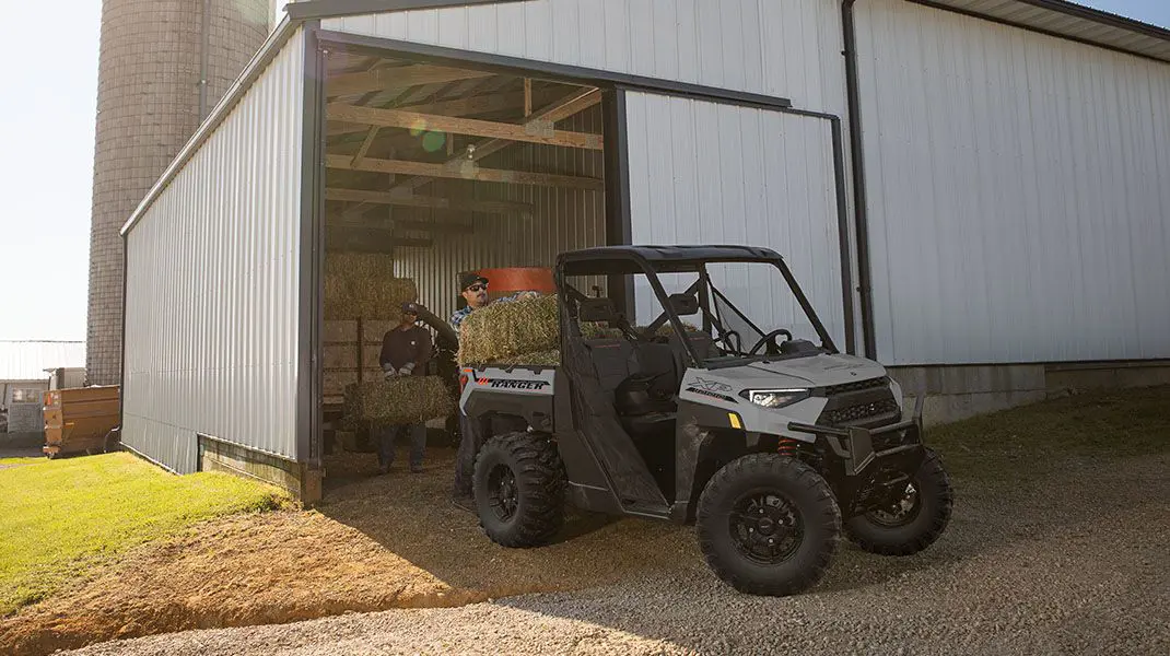 2 men loading square bales into cargo box on their Ranger XP 1000 Trail Boss