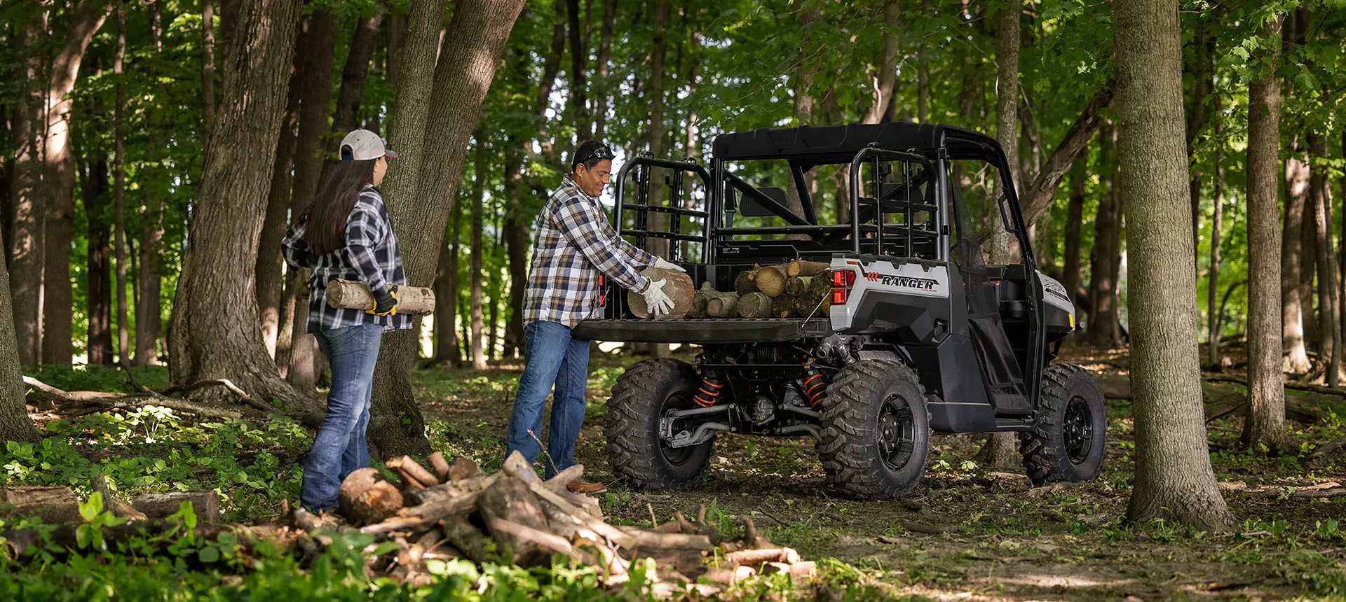 2 people loading firewood into cargo box on their Ranger XP 1000 Trail Boss