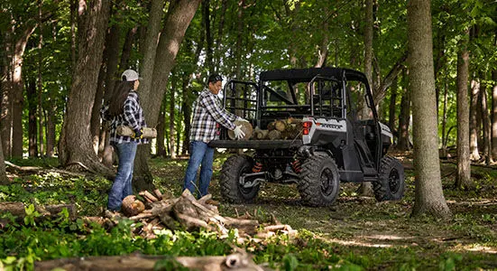 2 people loading firewood into cargo box on their Ranger XP 1000 Trail Boss
