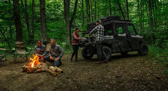 2 people unloading firewood from cargo box on their Ranger XP 1000 Trail Boss and having a fire