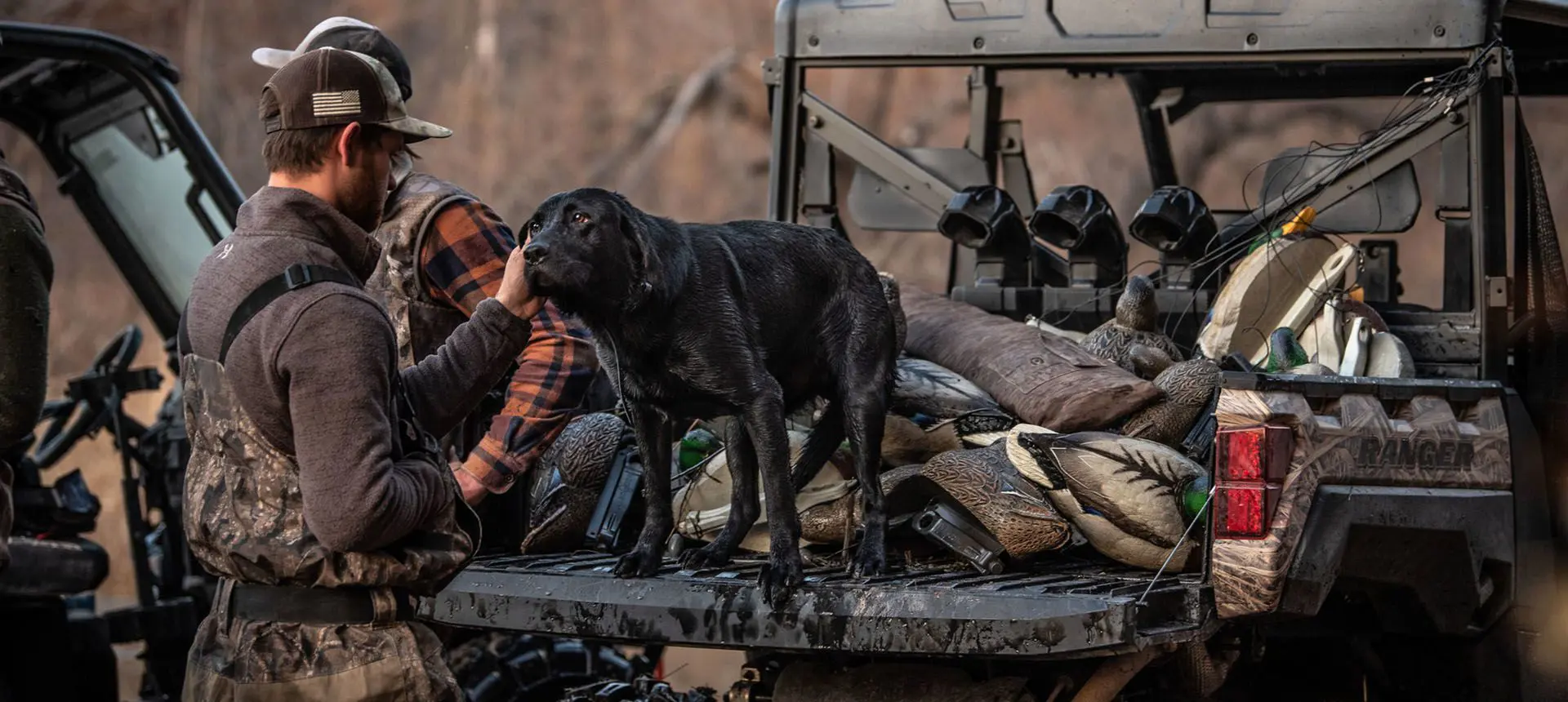 hunter getting his dog out of the cargo box of his polaris ranger xp 1000 waterfowl edition utv