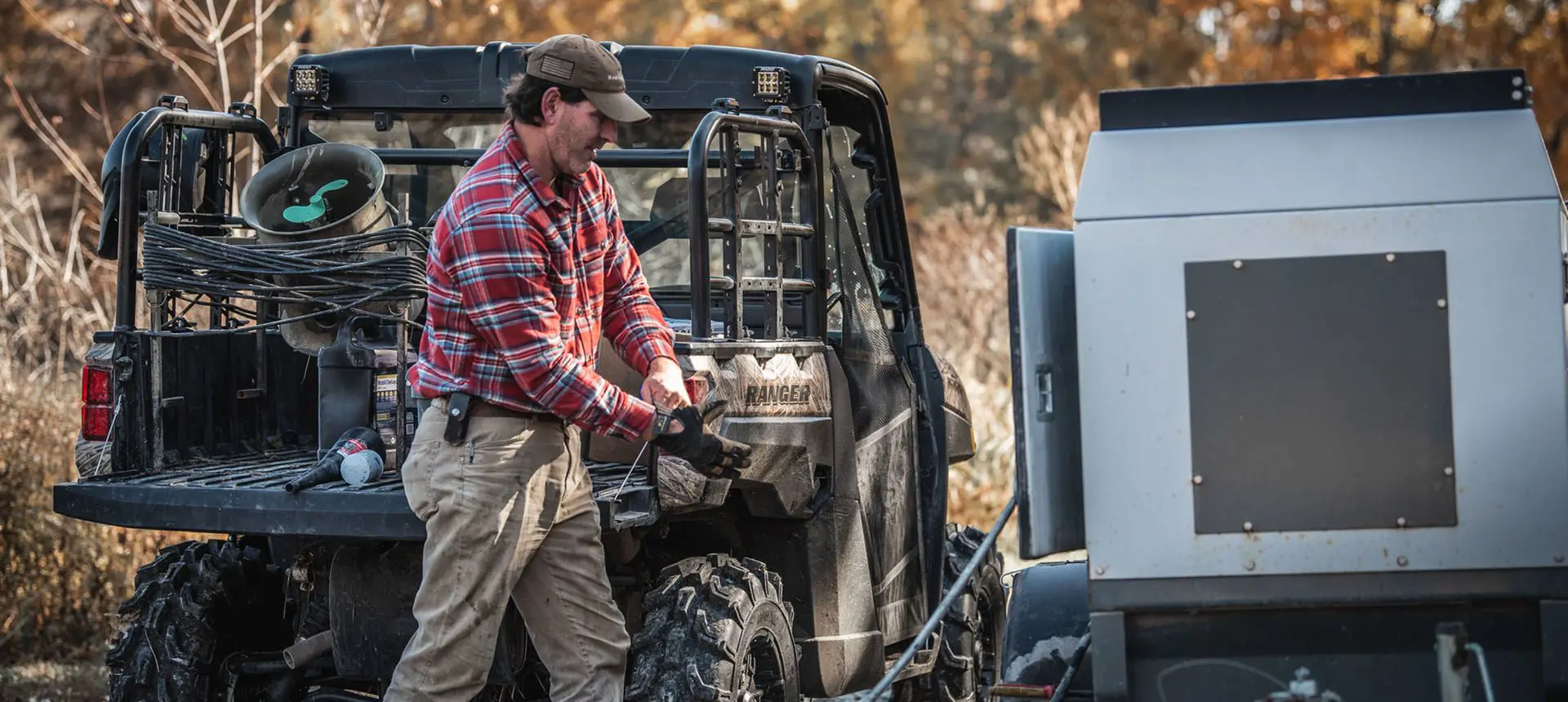 man putting on gloves to work with gear in the cargo of his polaris ranger xp 1000 waterfowl edition utv