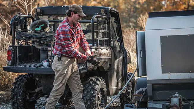 man putting on gloves to work with gear in the cargo of his polaris ranger xp 1000 waterfowl edition utv