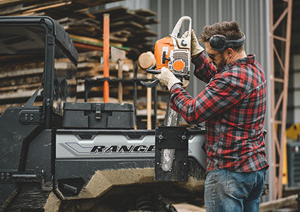 Man storing a saw into cargo box on his Ranger XP 1000