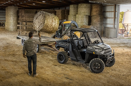 Farmers loading hay bales onto a trailer attached to their RANGER XP 1000