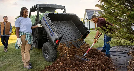 Famille déchargeant du paillis du coffre de son VUTT Ranger SP 570