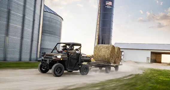 VUTT Polaris RANGER XP 1000 tirant une remorque avec des balles de foin sur une ferme