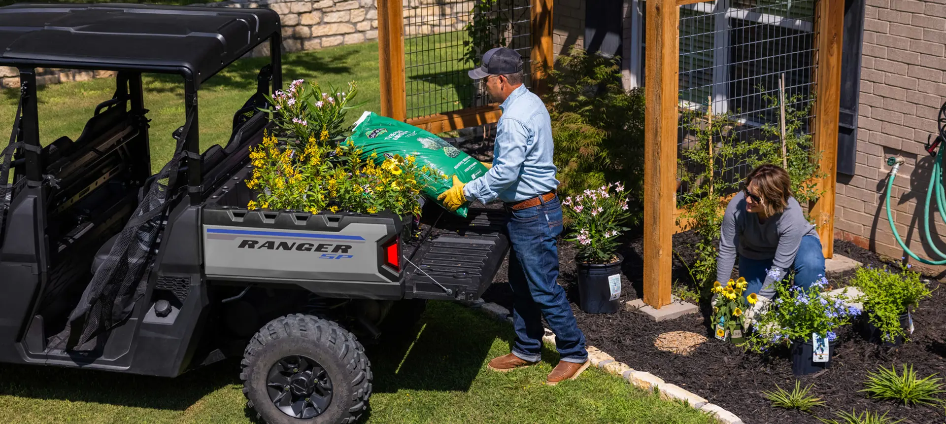 Man loading soil into the cargo box of his Ranger Crew SP 570 UTV