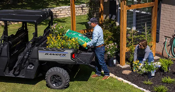 Man loading soil into the cargo box of his Ranger Crew SP 570 UTV