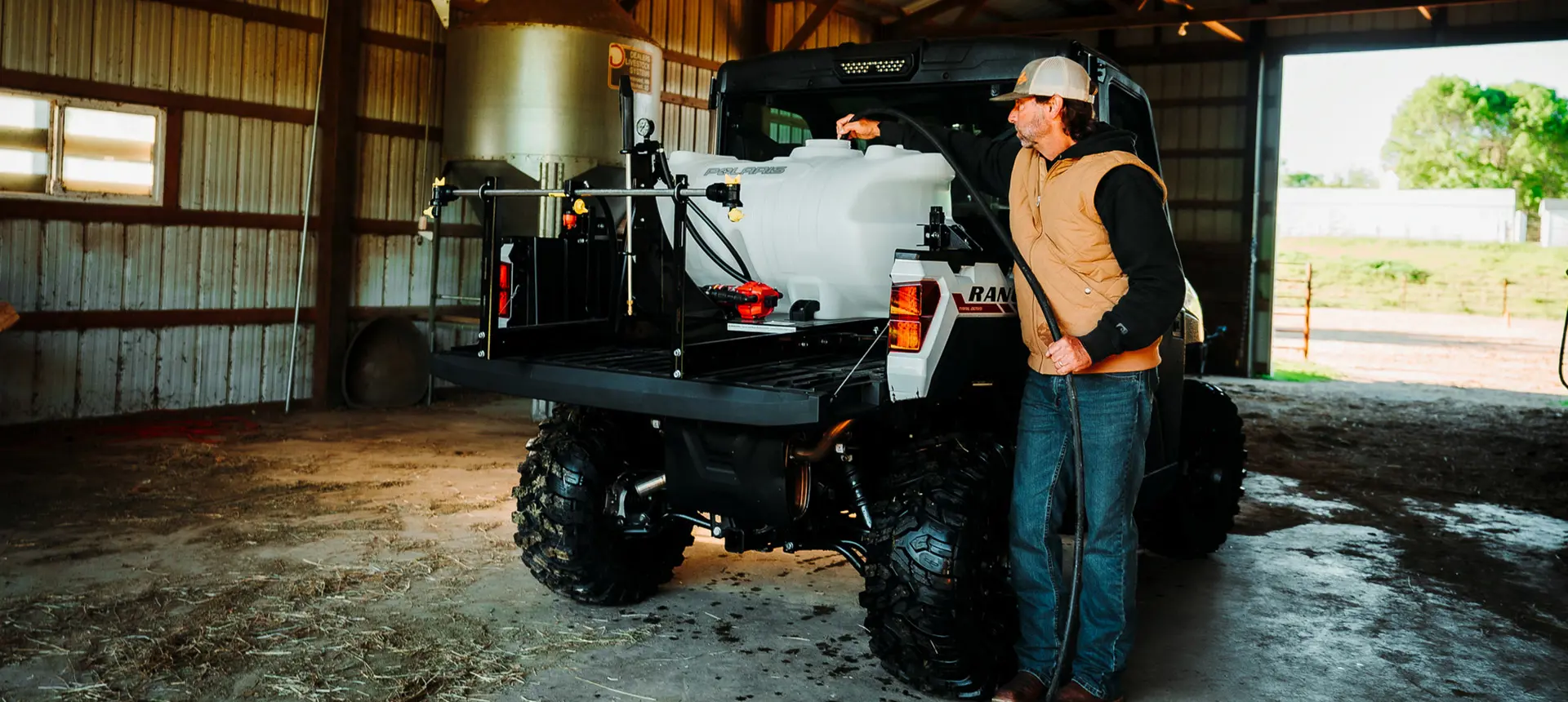 man loading water into a irrigation tank in the cargo box of his ranger xp 1000 northstar edition trail boss utv