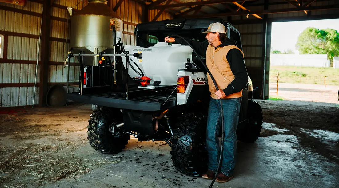 man loading water into a irrigation tank in the cargo box of his ranger xp 1000 northstar edition trail boss utv