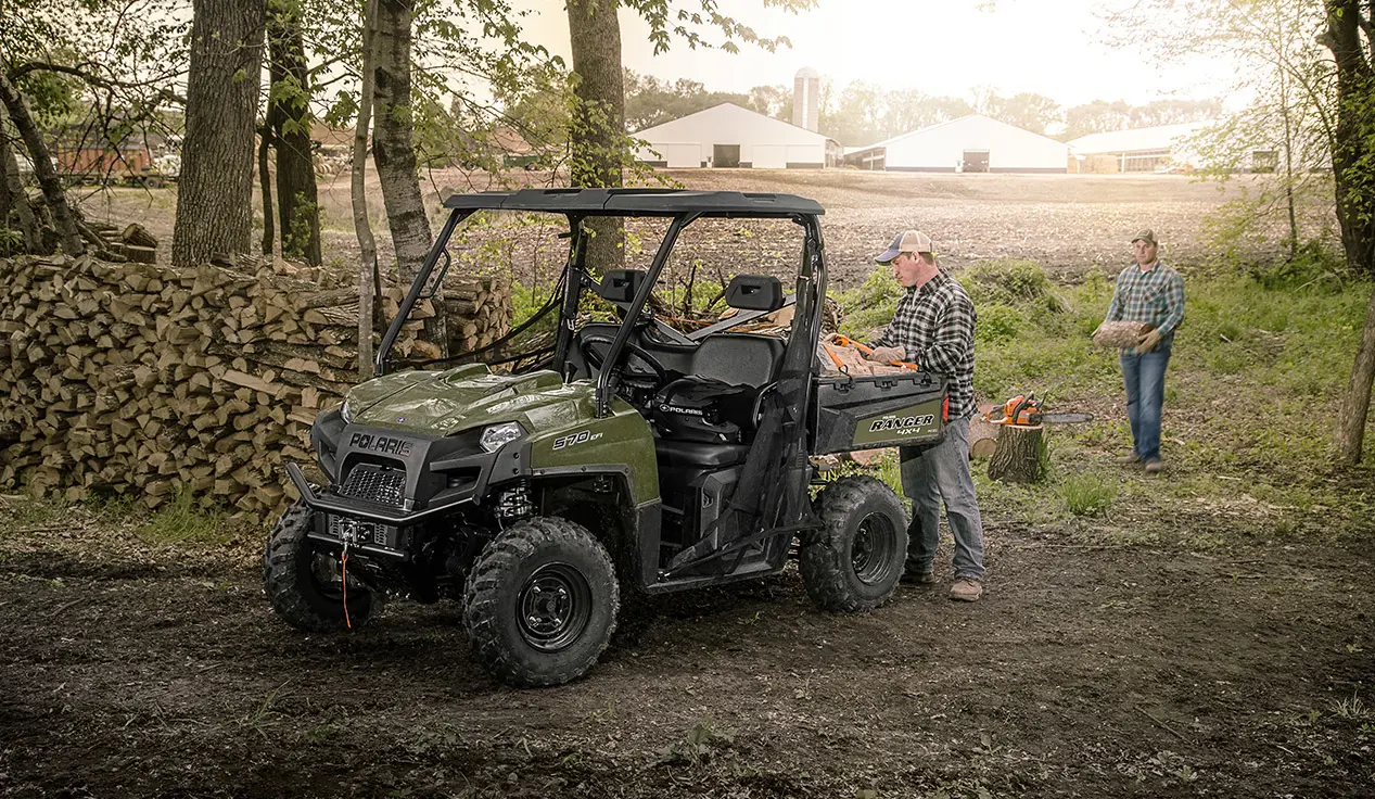 man loading wood into the cargo box on his ranger 570 full-size utv
