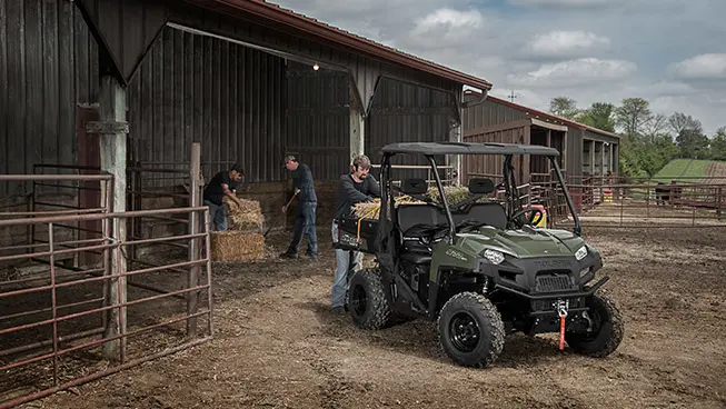 farmers loading square bales into the cargo box on their ranger 570 full-size utv