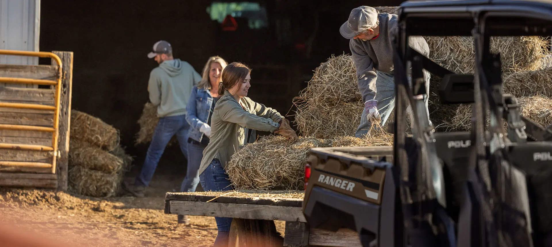 family loading hay onto a trailer pulled by their ranger crew xp 1000 utv