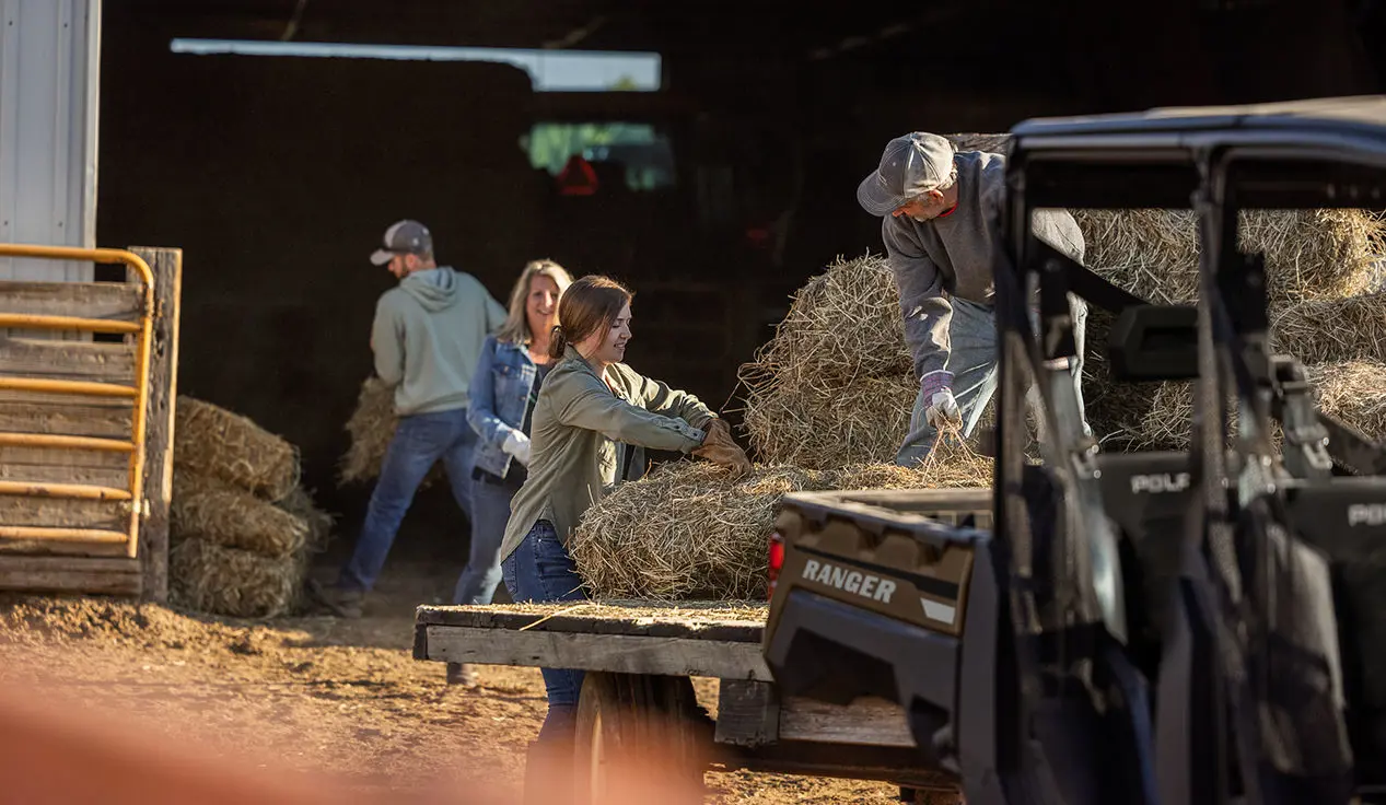 family loading hay onto a trailer pulled by their ranger crew xp 1000 utv