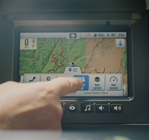 A finger selecting map layers on the Polaris RIDE COMMAND touchscreen, displaying off-road trail information.