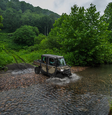 2025 RANGER CREW SP 570 NorthStar Edition UTV driving into ravine with LED headlights illuminated.