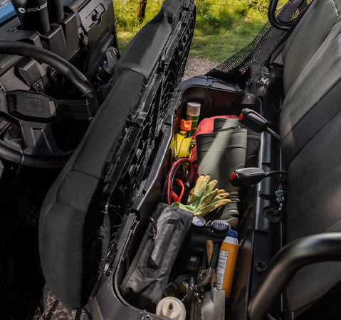 Easy-to-access under-seat storage bin in the 2025 RANGER SP 570 NorthStar Edition UTV filled with gear like boots, gloves, and tools.