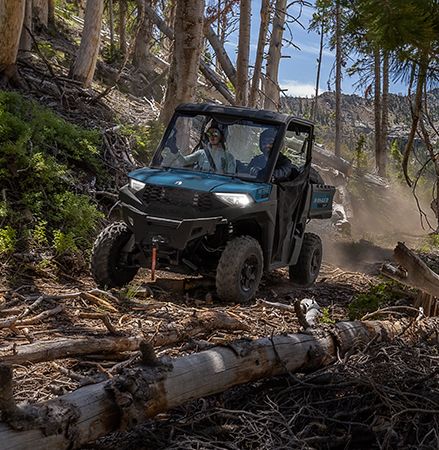 UTV Polaris RANGER SP 570 de 2025 conduciendo por un sendero rocoso con faros de LED iluminados.