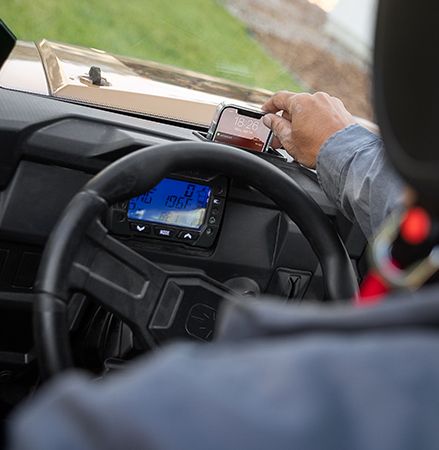 Persona cargando su teléfono usando el nuevo puerto USB en el tablero disponible en los UTV Polaris RANGER SP 570 Premium de 2025.