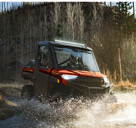 2025 Polaris RANGER XP 1000 NorthStar Edition UTV with factory-installed Pro Shield cab system driving through a ravine.