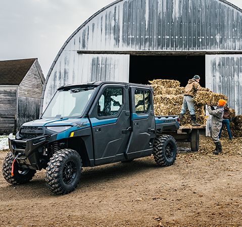 People loading square bales onto a trailer connected to a 2025 Polaris RANGER CREW XP 1000 NorthStar Edition UTV with the upgraded GEN 2 transmission.