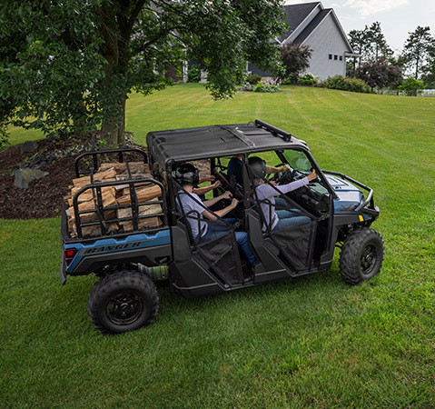 A family in a 2025 Polaris RANGER CREW XP 1000 UTV driving on a green lawn.
