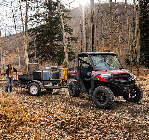 Two farmers using a welder being pulled on a trailer by their 2025 Polaris RANGER XP 1000 UTV.