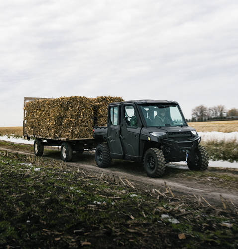 The capable 2026 Polaris RANGER CREW XP 1000 NorthStar Edition UTV pulling a trailer full of square bales.